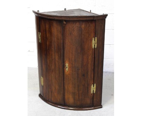 A George III mahogany bow-front corner cupboard with brass 'H' hinges and escutcheon, height 97.5cm.