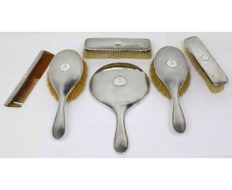 A George V hallmarked silver mounted engine-turned dressing table set comprising hand mirror, a pair of hair brushes, a pair 