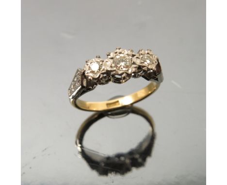 A three stone diamond ring, stamped '18ct', the graduated brilliant cuts illusion set, finger size K, weight 2.9g gross 