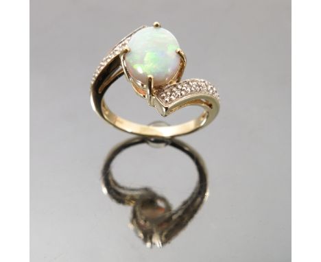 An opal and diamond 9ct gold ring, the cabochon to a cross over mount set with ten single cuts to each shoulder, finger size 