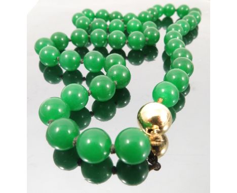 A uniform row of dyed green jade beads, the forty-four beads of approximately 1.2cm in diameter, to a plain spherical clasp, 