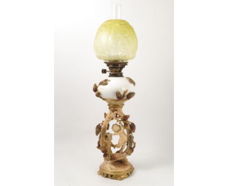 A Moores Irish oil lamp, the body with putti in a rustic arbour, with fir cones, with yellow glass shade, height 30.5ins 