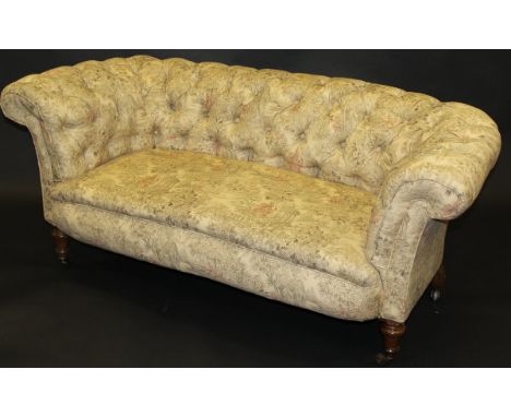 A late 19th Century buttoned back Chesterfield style sofa in pale beige upholstery with classical garden pattern, on turned m