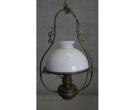 An Art Nouveau style scrolling design brass ceiling oil lamp with milk glass shade. H.80 x D.40cm 