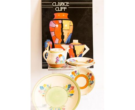 A group of Clarice Cliff; tea pot, saucers and a plate, together with a Clarice Cliff reference book.