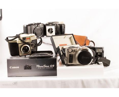A quantity of cameras: Canon EOS 1x camera plus Canon G9 Powershot, Minox 35GT, Olympus camera and Kodak Crista three brownie