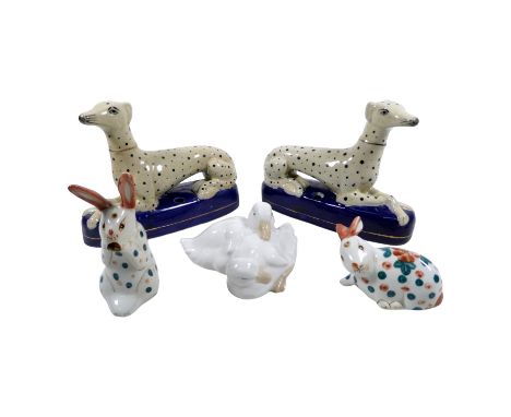 A pair of Staffordshire style greyhounds spill holders - the recumbent spotted dog laying on blue pillows, width 19cm, togeth