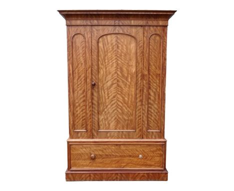 A Victorian satin birch wardrobe - the moulded cornice above an arched panel door, with a drawer fitted to the plinth base, 1