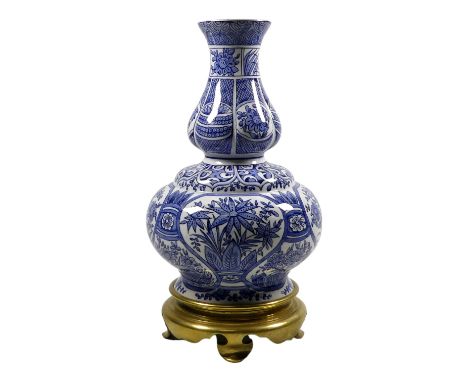 A late 19th century English blue and white lamp base - of double gourd form decorated with flowers and raised on a brass ring
