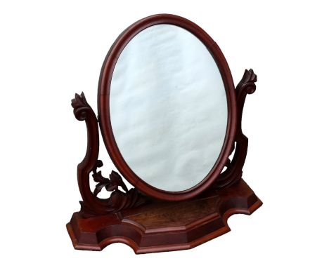 A Victorian mahogany toilet mirror - the oval plate flanked by pierced supports, on a plinth base incorporating a lidded comp