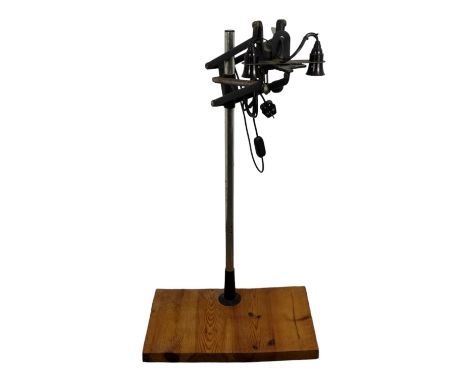 A 20th century industrial work lamp - formed from a photography enlarger, the pair of lamps mounted on a post above a pine ba