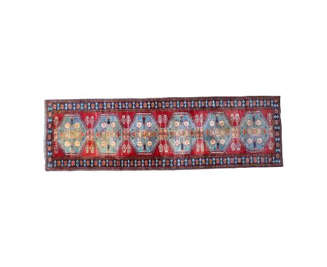 A Bokhara runner - with six light blue medallions on a red ground within a blue border, 286cm x 86cm