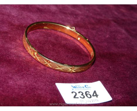 A gold coloured bangle, boxed.