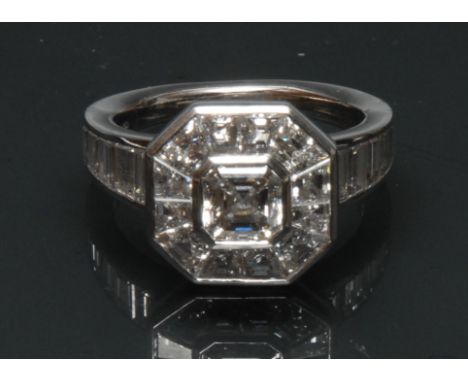 An Art Deco style diamond cluster ring, central square emerald cut diamond approx 1.03ct, colour H, clarity VVS1, surrounded 