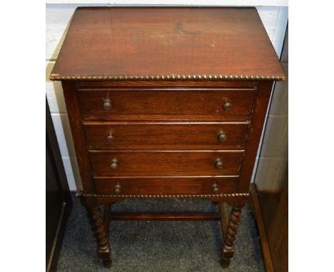 An early 20th century oak music cabinet, moulded frieze above faux drawers, barley twist supports.