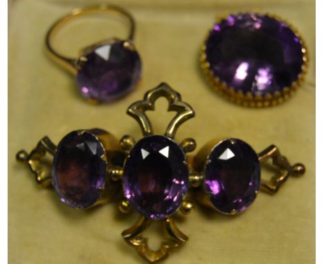 A 9ct gold purple stone solitaire ring, claw set, pierced sides, gross weight 4.8g; a gilt metal oval brooch set with a purpl