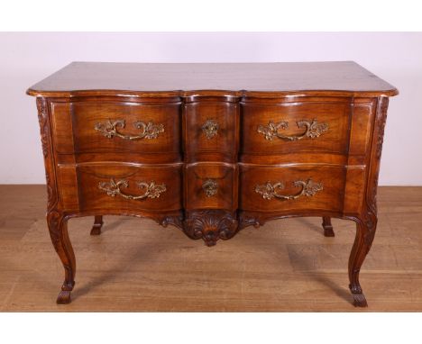 Notenhouten commode in Louis XV-stijl met in het gebogen front twee laden. Het geheel versierd met verguld bronzen beslag br.