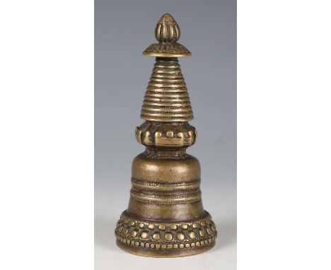A Tibetan bronze stupa, 12th/13th century, of bell shaped form, the lotus knop finial above a ridged spire and gallery, on a 