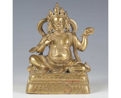 A Sino-Tibetan gilt bronze figure of Kubera, 18th century, modelled seated wearing an ornate headdress, beaded jewellery, dho