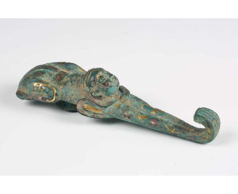 A Chinese gold and silver inlaid bronze belthook, Han dynasty or later, with verdigris patination, cast in the form of a yogi