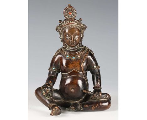 A Tibetan brown patinated bronze figure of Kubera, 17th/18th century, modelled seated, holding a jewel in his right hand and 