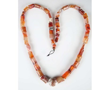 A Tibetan agate bead necklace, comprising forty-seven irregular cylindrical beads and a larger spherical bead with coral mark