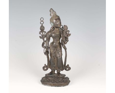 A Tibetan brown patinated bronze figure of Tara, 18th century, modelled standing wearing ornate headdress, bead jewellery and