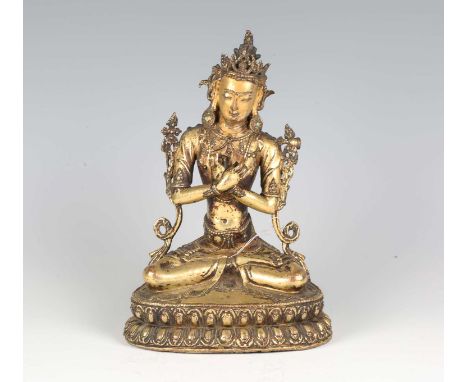 A Tibetan gilt bronze figure of Vajradhara, 15th century, modelled seated in dhyanasana with hands held before his chest in v