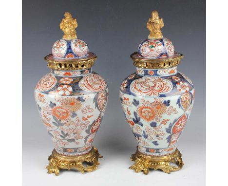 A pair of Japanese Imari porcelain jars and domed covers, 18th century, with later gilt metal mounts, each ovoid body painted