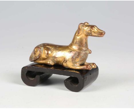 A Chinese gilt bronze figure of a dog, Han dynasty, the hound modelled in a recumbent pose, length 6.8cm. Provenance: the Ala
