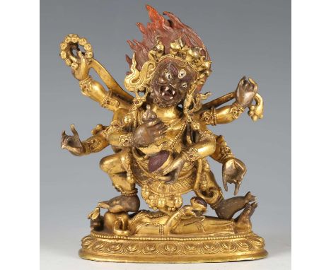 A Tibetan gilt bronze figure of Mahakala, 18th century, the six-armed deity modelled standing on a prostrate figure with elep