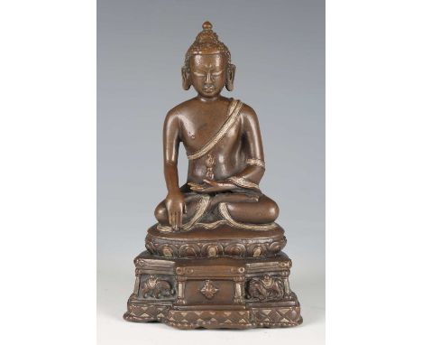 A North-east Indian brown patinated bronze figure of Akshobhya, 16th century, modelled seated in dhyanasana with hands held i