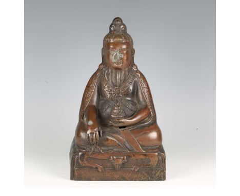 A Tibetan brown patinated bronze figure of a mahasiddha, 20th century, modelled seated in dhyanasana with hands held in bhumi