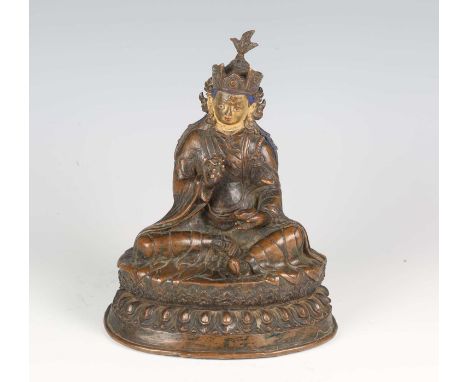 A Tibetan brown patinated bronze figure of Padmasambhava, 16th century, modelled seated on a lotus throne, wearing a long rob