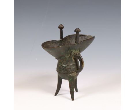 China, an archaistic-style bronze ritual pouring vessel, jue, Qing dynasty (1644-1912), raised on tripod legs, with two uprig