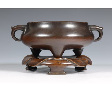 China, a tripod bronze censer and stand, Qing dynasty (1644-1912), the bulbous vessel standing on three tapered feet and cast