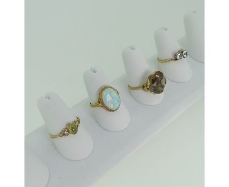 Four 9ct yellow gold Rings; one set oval opal, one smokey quartz, one a crossover with white pastes, the other a small perido