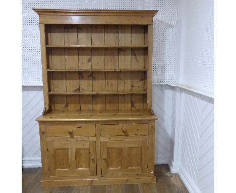 An antique pine kitchen Dresser, with moulded cornice above a three tier plate rack, with two drawers and two cupboards below