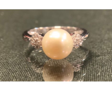 A diamond and cultured pearl ring, central creamy white cultured pearl mounted between two seven stone round brilliant cut da