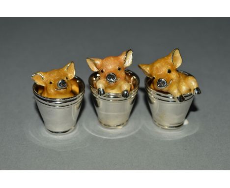 A SET OF THREE ELIZABETH II SILVER AND ENAMEL PIGLETS IN BUCKETS, possibly by Saturno of Italy, bears import marks for London