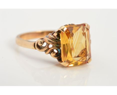A CITRINE RING, designed as a rectangular citrine within a four claw setting with scrolling detail to the shoulders, stamped 