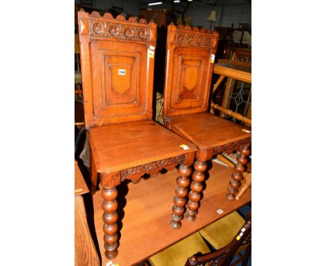 A PAIR OF VICTORIAN CARVED OAK HALL CHAIRS with shield back on bobbin turned front legs