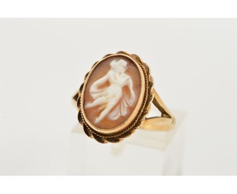 A 9CT GOLD CAMEO RING, designed as an oval cameo depicting a lady dancing to the double rope twist surround, to the bifurcate