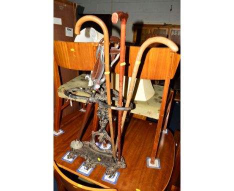 A VICTORIAN CAST IRON UMBRELLA STAND containing three walking sticks and a shooting stick (5)