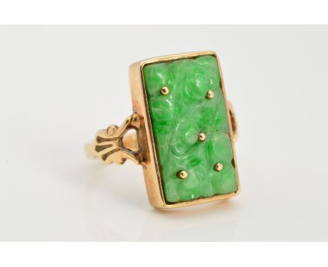 A 9CT GOLD JADE RING, designed as a carved rectangular jade panel within a collet setting to the bifurcated shoulders, with 9