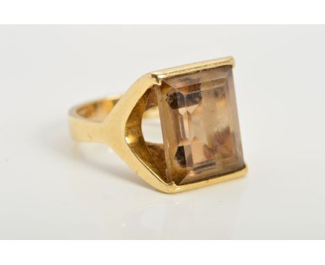 A 9CT GOLD SMOKY QUARTZ RING, designed as a rectangular smoky quartz within an abstract setting with V-shapes to either side,