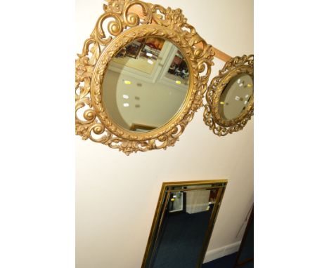 A LARGE FOLIATE GILT RESIN CIRCULAR WALL MIRROR, together with a similar smaller wall mirror and a modern bevelled edge wall 
