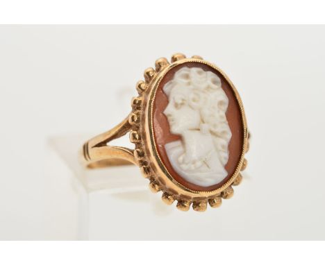 A 9CT GOLD CAMEO RING, designed as an oval cameo depicting a lady in profile within a collet setting and beaded surround to t