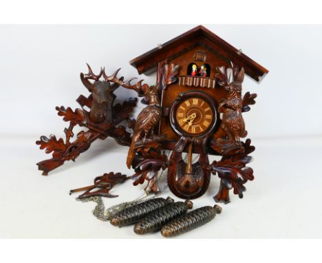 A German cuckoo clock with figural carousel, decorated with game, having three pinecone weights and pendulum. [W]