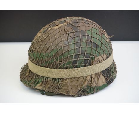 A British Military Helmet Complete With Liner, Camouflage Cover, Mesh Netting And Strap. 